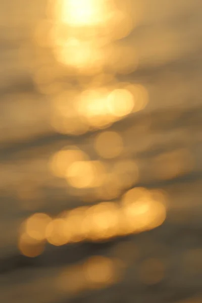 Abstraktes goldenes Sonnenlicht Bokeh auf blauem Meereswasser Hintergrund. — Stockfoto