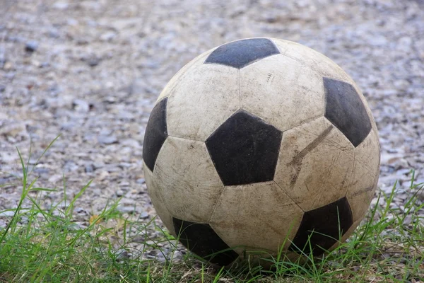 An old football or soccer ball on crushed gravel yard. — Stock Photo, Image