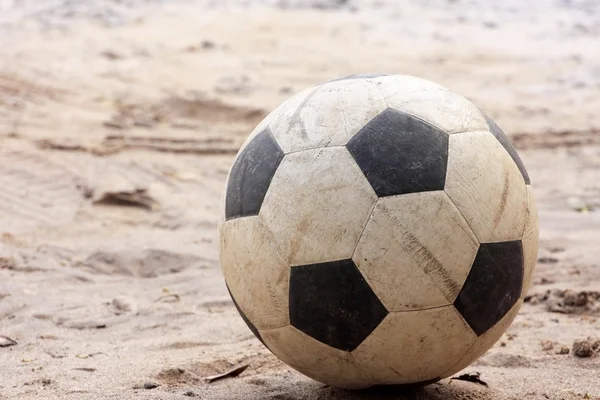 An old football or soccer ball on sand. — Stock Photo, Image