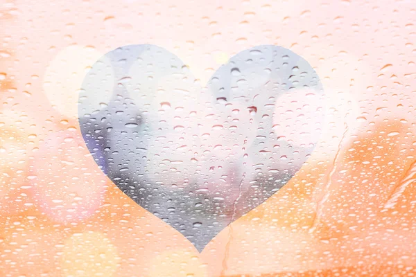 Regen druppels op venster met lichte bokeh op hart frame abstracte ba — Stockfoto