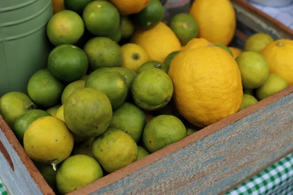 Limone e lime in vendita in scatola di legno . — Foto Stock