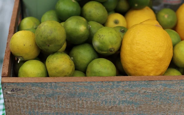 Limone e lime in vendita in scatola di legno . — Foto Stock