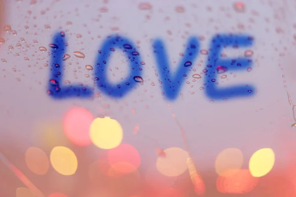 Gotas de chuva e a palavra amor escrevem na janela com luz bokeh, r — Fotografia de Stock