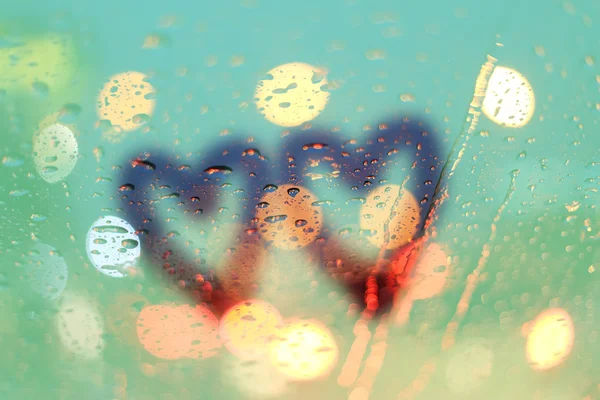 Regen druppels en twee harten schrijven op venster met lichte bokeh, regen — Stockfoto