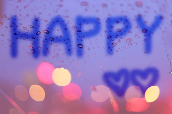 Krople deszczu i szczęśliwy słowo napisać na okno z światła bokeh, — Zdjęcie stockowe