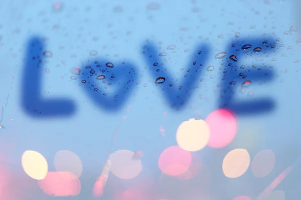 Regen druppels met het woord liefde wwrite op venster met lichte bokeh, — Stockfoto