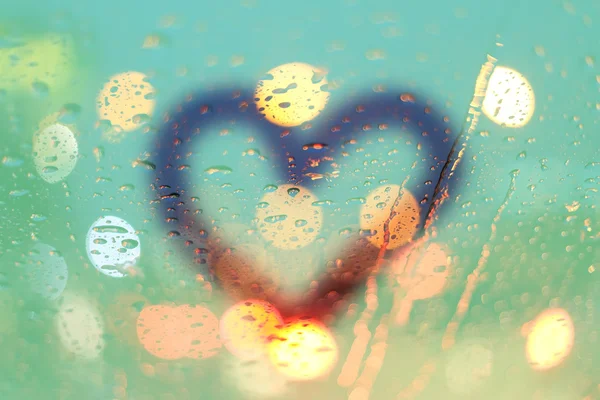 Gotas de chuva e coração escrevem na janela com luz bokeh, mar chuvoso — Fotografia de Stock