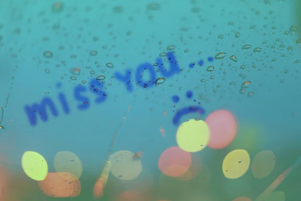 Chuva cai com a palavra miss você escreve na janela com luz bok — Fotografia de Stock