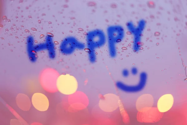 Krople deszczu i szczęśliwy słowo napisać na okno z światła bokeh, — Zdjęcie stockowe