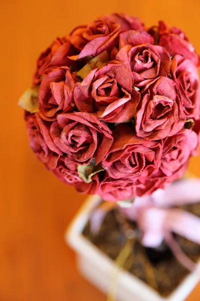 Bukiet róż sztuczne w małym garnku na drewnianym stole. — Zdjęcie stockowe