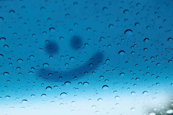 Rosto sorridente escrever em vidro com gota de chuva, fundo abstrato . — Fotografia de Stock