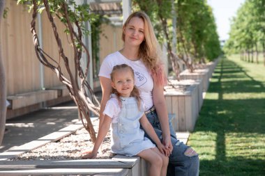 Güzel anne ve küçük kızı yaz parkında birlikte yürüyorlar. Krasnodar