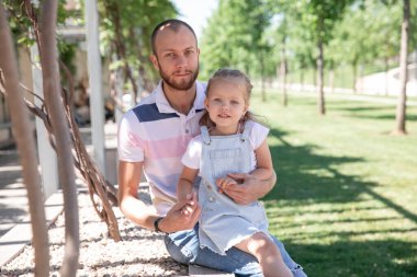 Küçük, güzel bir kızı olan baba yeşil bir parkta yürüyor. Krasnodar