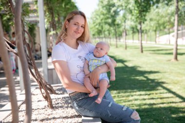 Küçük bir oğlu olan bir anne yeşil bir parkta yürüyor. Krasnodar Parkı