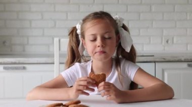 Mutfakta kurabiye yiyen tatlı küçük kız. Güzel çocuk kurabiye yer.