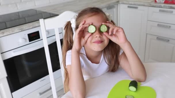 子供は台所で健康的な食べ物を食べる ビタミン 菜食主義 菜食主義の概念 子供は目の前にキュウリのマグカップを持っていて — ストック動画
