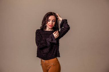 Bir ton bej arka planda siyah uzun saçlı, ince, güzel bir genç kız. Kahverengi pantolonlu ve siyah bluzlu kadın. Boşluğu kopyala