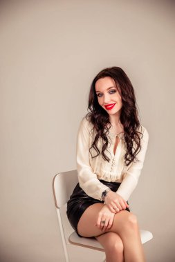 Onun güzel görünümlü portresi... oldukça sevimli... çekici... hoş, hoş, güzel... dalgalı saçlı kız... kollarını katlamış... gri pastel arka plan üzerine izole edilmiş..