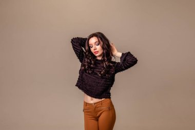 Bir ton bej arka planda siyah uzun saçlı, ince, güzel bir genç kız. Kahverengi pantolonlu ve siyah bluzlu kadın. Boşluğu kopyala