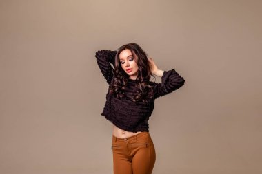 Bir ton bej arka planda siyah uzun saçlı, ince, güzel bir genç kız. Kahverengi pantolonlu ve siyah bluzlu kadın. Boşluğu kopyala