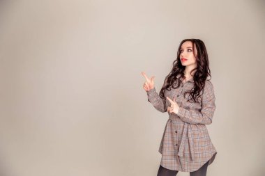 Uzun saçlı güzel bir esmerin gülümseyen portresi. İş kadını gri arka plana bakıp duruyor. Kopyalama alanı