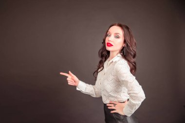 Uzun saçlı güzel bir esmerin gülümseyen portresi. İş kadını gri arka plana bakıp duruyor. Kopyalama alanı