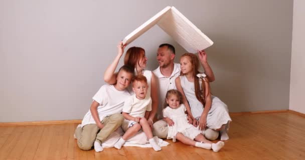 家庭で段ボール屋根の下に座って幸せな家族。保険の概念 — ストック動画