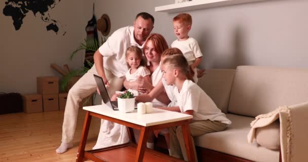 Private education concept. Happy family young parents couple and cute kids using laptop looking at computer screen enjoying watching funny social media video doing online shopping relaxing on sofa at — Stock Video