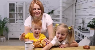 Anne iki kızıl çocuğuna yemek yediriyor.