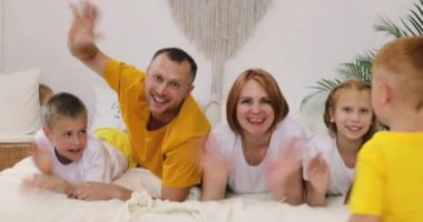 Yatağında çocukları olan mutlu bir aile.