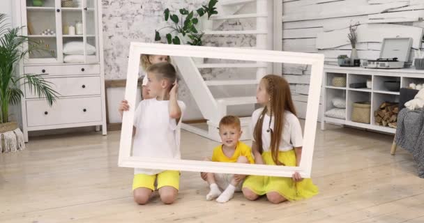 Дети держат рамку и улыбаются — стоковое видео