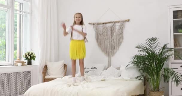 赤い女の子ティーンで白いジャージーと黄色のスカートはベッドの上でジャンプします — ストック動画