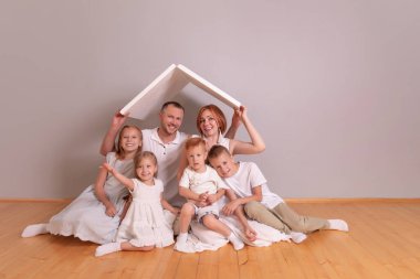 Karton çatının altında oturan mutlu, geniş bir aile. Sigorta konsepti. Boşluğu kopyala