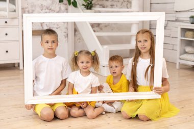 Elinde resim çerçevesi olan gülümseyen çocuklar. Dört çocuk. erkek ve kız kardeşler