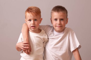 Mutlu Gençler ve Çocuk Portresi. İki kardeş. Kırmızı ve sarışın. Küçük ve büyük çocuklar. İki kardeş birbirlerine sarılırlar.