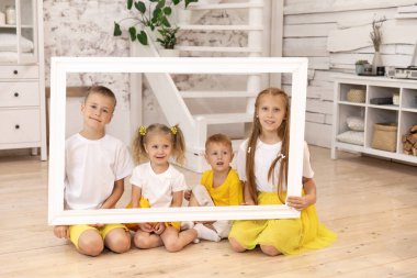 Elinde resim çerçevesi olan gülümseyen çocuklar. Dört çocuk. erkek ve kız kardeşler.