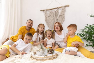 Beş kişilik bir aile ve kedileri sabahları yataklarında kahvaltı yapıyorlar.