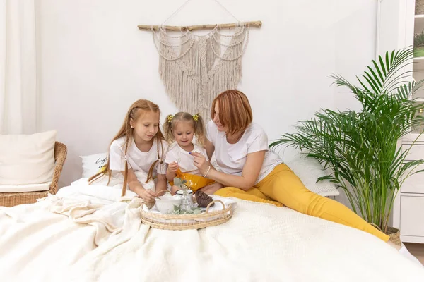 Family of five and their cat having breakfast in their bed in the morning