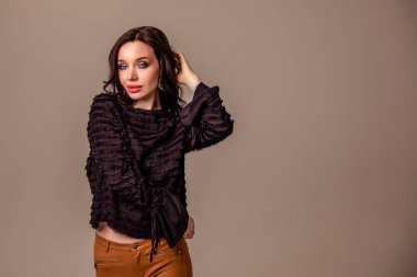 Bir ton bej arka planda siyah uzun saçlı, ince, güzel bir genç kız. Kahverengi pantolonlu ve siyah bluzlu kadın. Boşluğu kopyala