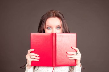 Modern iş kadını elinde bir defter tutuyor. Siyah arka planda beyaz bluzlu genç bir iş kadını..