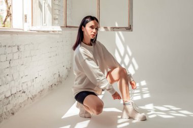 Güzel bir kadın yerde bacaklarıyla oturuyor.