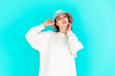 Kot şapkalı güzel bir kızın portresi ve mavi arka planda beyaz bir kapüşonlu. Spor konsepti, yaz