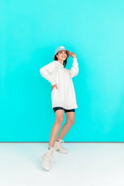 Kot şapkalı güzel bir kızın portresi ve mavi arka planda beyaz bir kapüşonlu. Spor konsepti, yaz