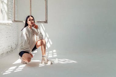 Spor kıyafetli güzel esmer kız pencere kenarında oturuyor.