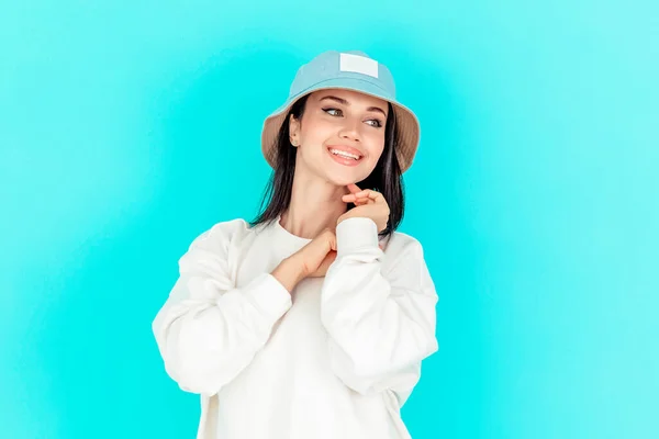 portrait of a beautiful girl in a denim cap and a white hoody on a blue background. concept of sport, summer