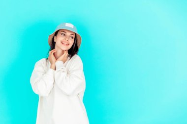 Kot şapkalı güzel bir kızın portresi ve mavi arka planda beyaz bir kapüşonlu. Spor konsepti, yaz