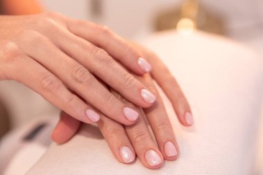 Manikürcü güzellik salonundaki müşterinin elini tutuyor. Kuaförde manikür.