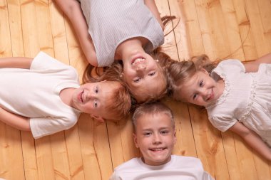 Dört çocuk yerde yatar ve kameraya bakar..