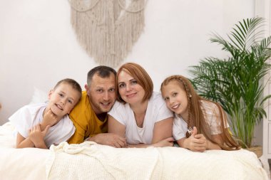 Mutlu bir aile yatakta yatarak eğleniyor. Mutlu aile yatakta yatıyor.