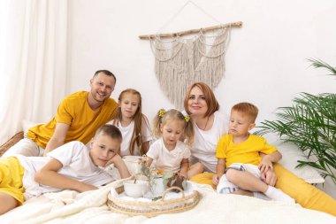 Beş kişilik bir aile ve kedileri sabahları yataklarında kahvaltı yapıyorlar.